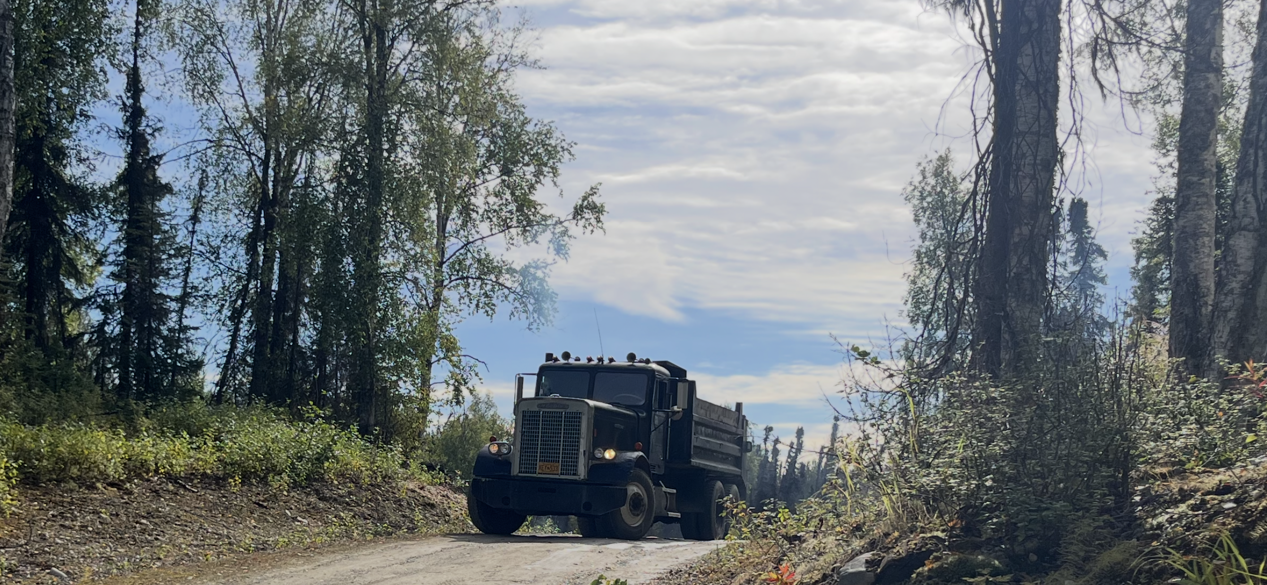 Dump truck driving through Alaskan forest